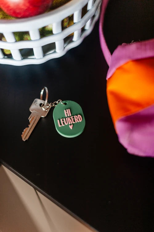 Verras een vriendin, collega of familielid met deze speelse sleutelhanger met de tekst ‘Hi leukerd’. Dit vrolijke kleinigheidje zorgt elke dag voor een glimlach. Met een frisse groene kleur en roze opdruk is deze sleutelaccessoire een opvallende, positieve toevoeging aan elke sleutelbos of tas. Perfect als traktatie, spontaan cadeautje of om iemand zomaar extra vrolijkheid te geven.